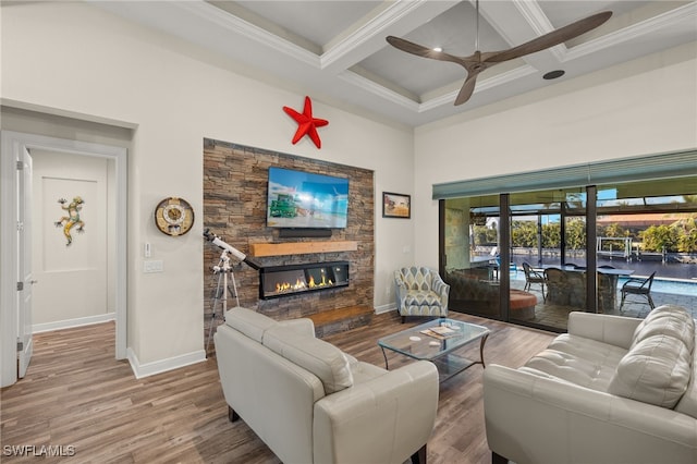 living room with coffered ceiling, ceiling fan, hardwood / wood-style flooring, beamed ceiling, and a stone fireplace