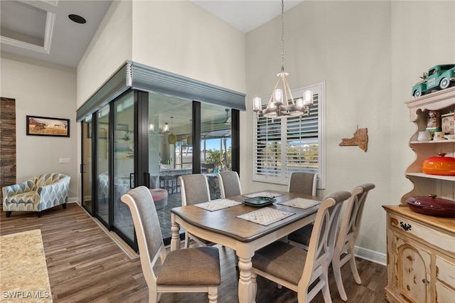 dining space with a chandelier, a towering ceiling, and dark wood-type flooring