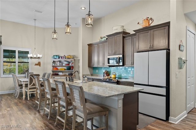 kitchen with decorative backsplash, appliances with stainless steel finishes, a breakfast bar, dark brown cabinetry, and sink