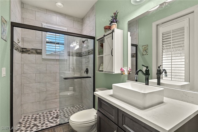 bathroom featuring toilet, vanity, a shower with shower door, and hardwood / wood-style flooring