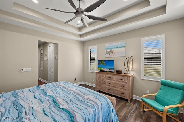 bedroom with a tray ceiling, ceiling fan, and dark hardwood / wood-style floors