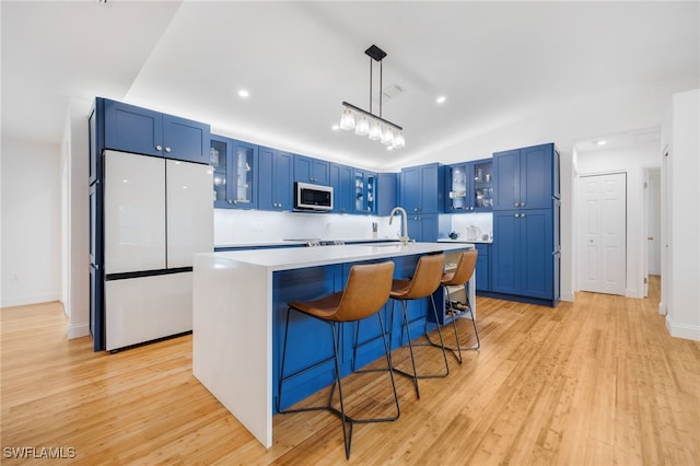 kitchen featuring a kitchen breakfast bar, white fridge, light wood-type flooring, pendant lighting, and blue cabinets