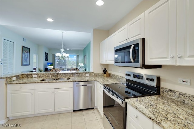 kitchen with a notable chandelier, light stone counters, a sink, appliances with stainless steel finishes, and white cabinets
