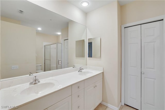 bathroom featuring toilet, vanity, tile patterned floors, and a shower with shower door