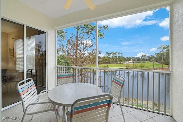 sunroom with ceiling fan and a water view