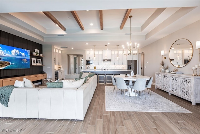 living room featuring sink, a chandelier, and beamed ceiling