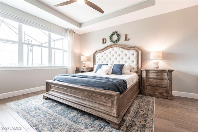 bedroom featuring light hardwood / wood-style floors, a tray ceiling, and ceiling fan