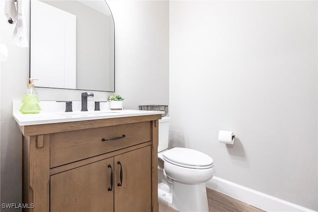 bathroom with vanity, toilet, and hardwood / wood-style floors