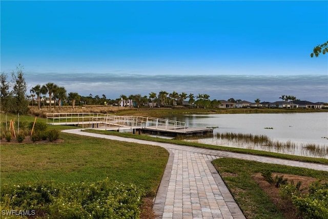 exterior space featuring a boat dock, a water view, and a yard