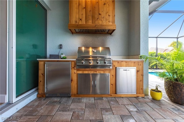 view of patio featuring exterior kitchen, a grill, and glass enclosure