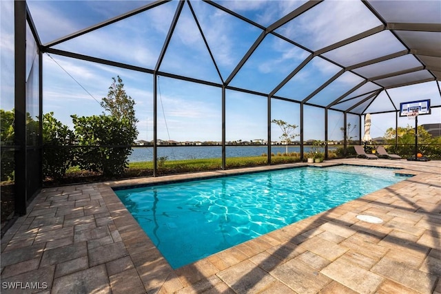 view of pool featuring glass enclosure, a water view, and a patio area