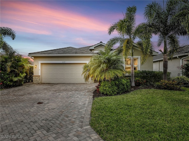 view of front facade with a garage, decorative driveway, a lawn, and stucco siding