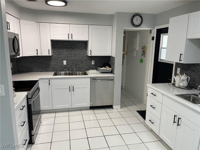 kitchen with appliances with stainless steel finishes, light countertops, a sink, and white cabinetry