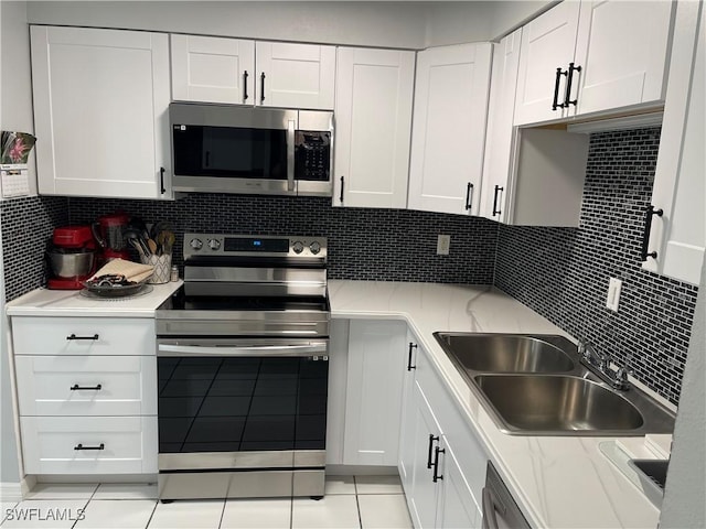 kitchen featuring stainless steel appliances, white cabinetry, a sink, and decorative backsplash