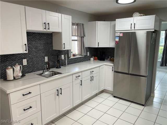 kitchen with white cabinetry, light countertops, a sink, and freestanding refrigerator