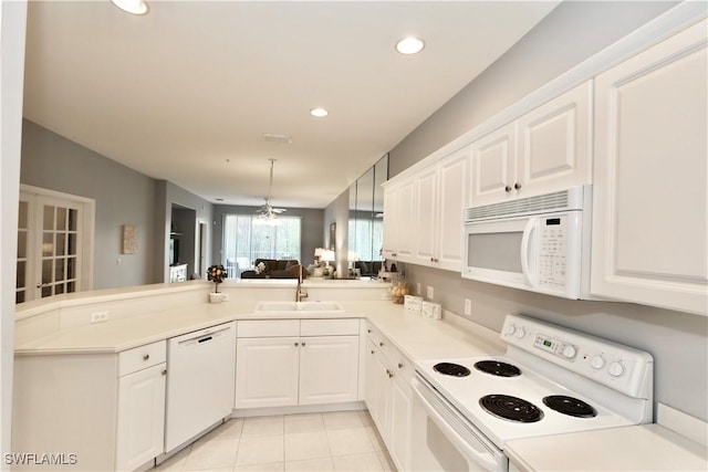 kitchen featuring light tile patterned floors, white cabinetry, kitchen peninsula, white appliances, and sink