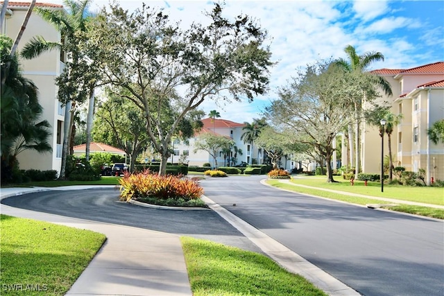 view of road with a residential view, street lighting, and sidewalks