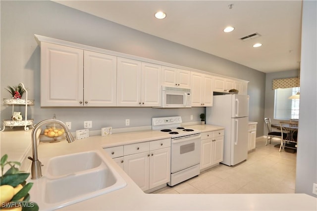 kitchen featuring white cabinetry, white appliances, recessed lighting, and a sink