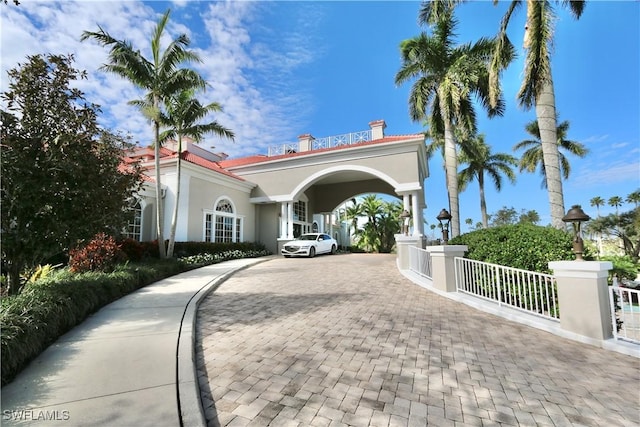 view of front of home featuring stucco siding, decorative driveway, a tile roof, and fence