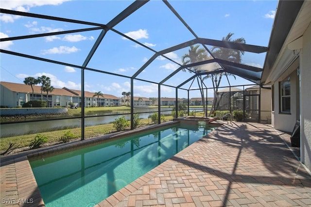 view of swimming pool featuring glass enclosure, a water view, and a patio