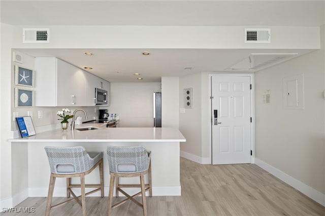 kitchen with kitchen peninsula, a breakfast bar, white cabinets, and sink