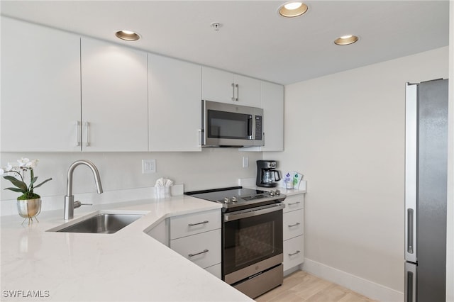 kitchen featuring white cabinetry, sink, light hardwood / wood-style floors, and appliances with stainless steel finishes