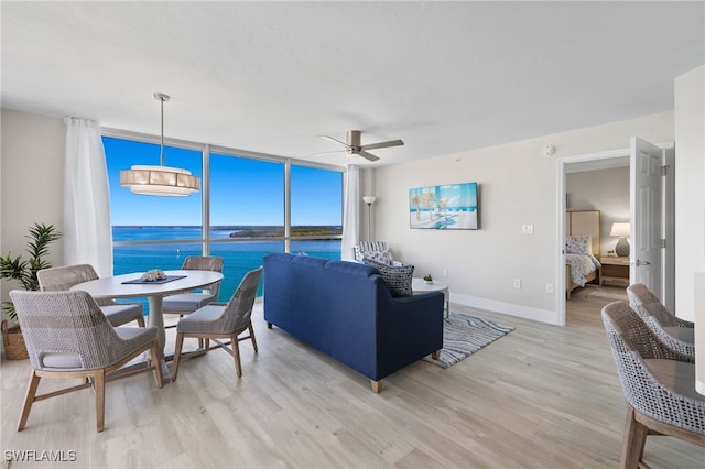 living room with ceiling fan, expansive windows, a water view, and light hardwood / wood-style floors