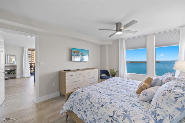 bedroom with ceiling fan, light hardwood / wood-style flooring, and multiple windows