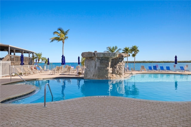 view of swimming pool with a patio, a water view, and pool water feature