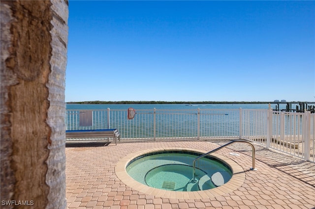 view of swimming pool with a water view and a hot tub