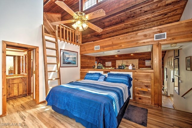 bedroom featuring high vaulted ceiling, wooden walls, light hardwood / wood-style flooring, ceiling fan, and wood ceiling