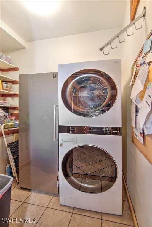 clothes washing area featuring light tile patterned floors and stacked washer and clothes dryer