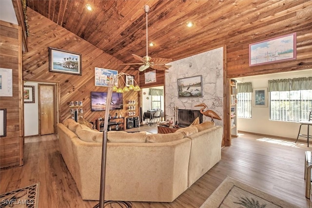 living room featuring high vaulted ceiling, ceiling fan, a fireplace, light hardwood / wood-style floors, and wood ceiling