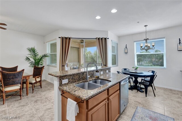 kitchen with sink, decorative light fixtures, dishwasher, an island with sink, and light stone countertops