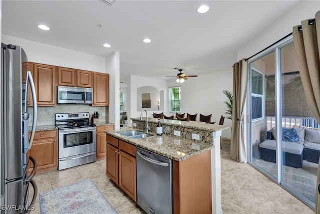 kitchen featuring appliances with stainless steel finishes, ceiling fan, a kitchen island with sink, and sink