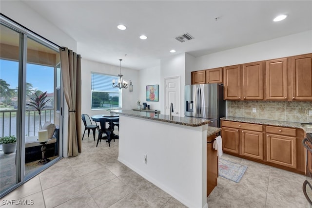 kitchen with hanging light fixtures, a notable chandelier, stainless steel refrigerator with ice dispenser, stone countertops, and tasteful backsplash