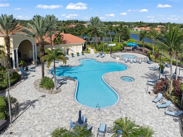 pool with a water view, a patio area, and a hot tub