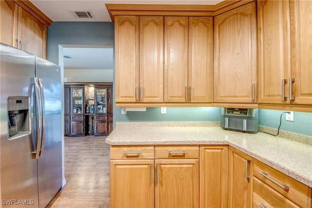 kitchen with light stone countertops, light hardwood / wood-style flooring, and stainless steel refrigerator with ice dispenser