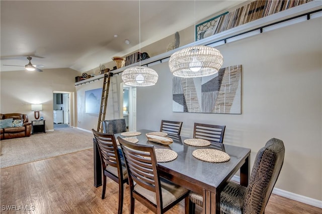 dining area featuring hardwood / wood-style floors, ceiling fan with notable chandelier, and lofted ceiling