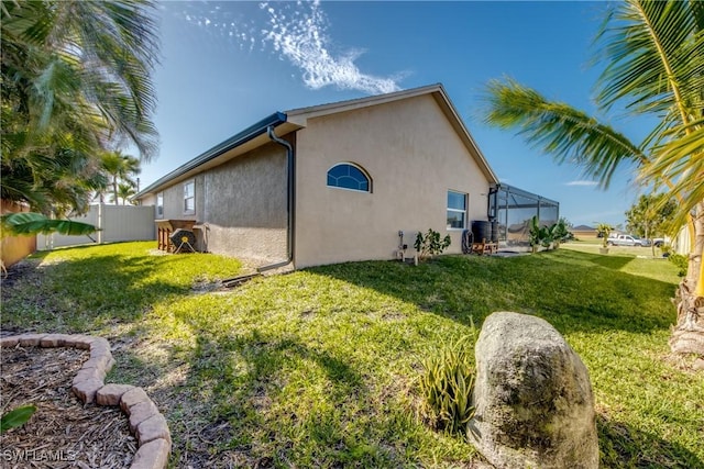 rear view of property featuring a lawn and glass enclosure