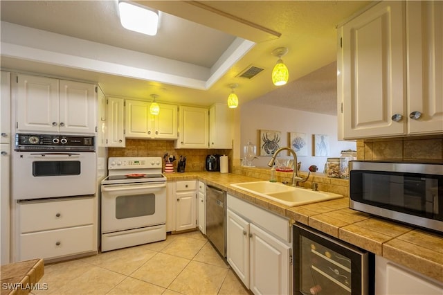 kitchen with white cabinets, sink, wine cooler, light tile patterned floors, and appliances with stainless steel finishes