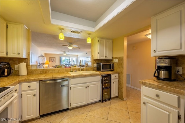 kitchen with tile counters, white cabinetry, and appliances with stainless steel finishes