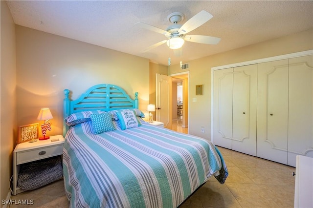 tiled bedroom featuring ceiling fan, a closet, and a textured ceiling