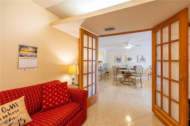 living room with ceiling fan, light tile patterned floors, a textured ceiling, and french doors