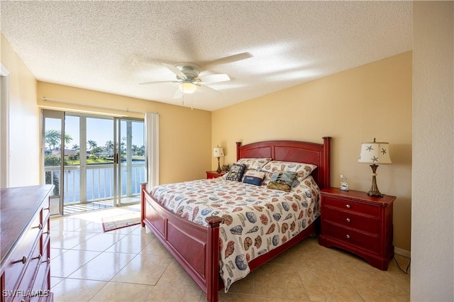 tiled bedroom featuring access to exterior, ceiling fan, a water view, and a textured ceiling