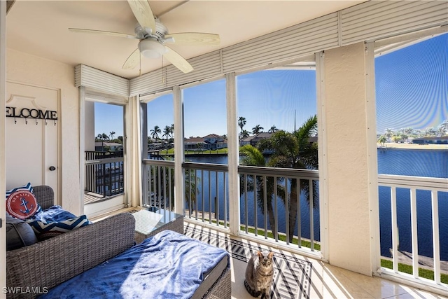 sunroom / solarium featuring ceiling fan and a water view