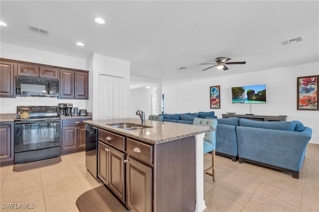 kitchen featuring dark brown cabinetry, ceiling fan, a kitchen island with sink, sink, and black appliances