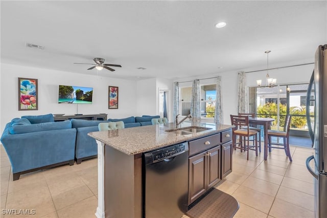 kitchen featuring sink, hanging light fixtures, black dishwasher, an island with sink, and stainless steel refrigerator