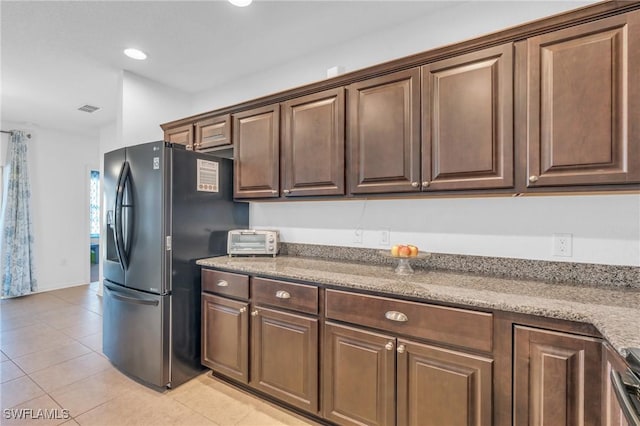 kitchen featuring light tile patterned flooring, light stone countertops, and stainless steel fridge with ice dispenser