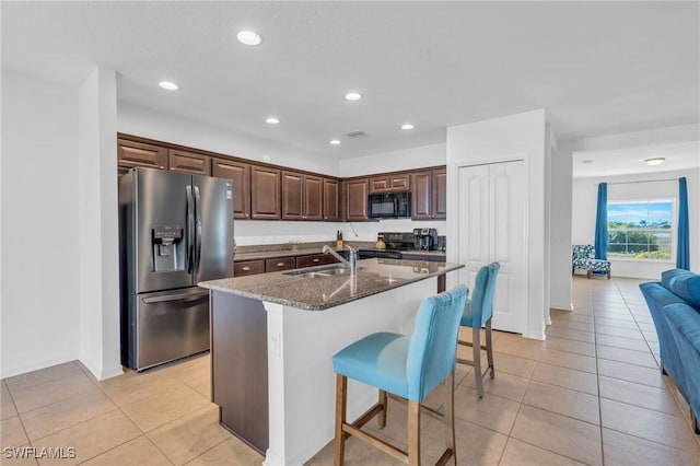 kitchen with sink, dark stone counters, a kitchen bar, a kitchen island with sink, and black appliances